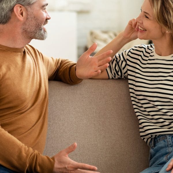 A couple sat on a sofa talking.