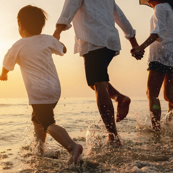 A family paddling in the sea at a beach.