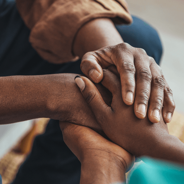 An elderly person and a young person holding hands.